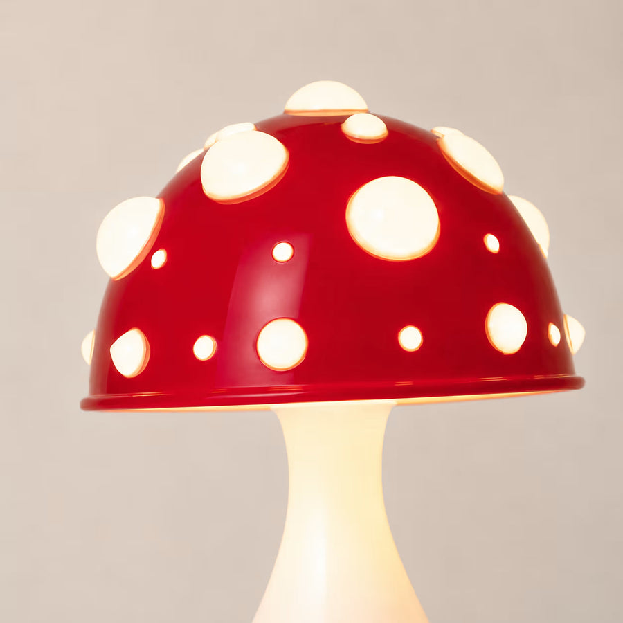 The Manita Lamp illuminated beneath its red mushroom-shaped dome