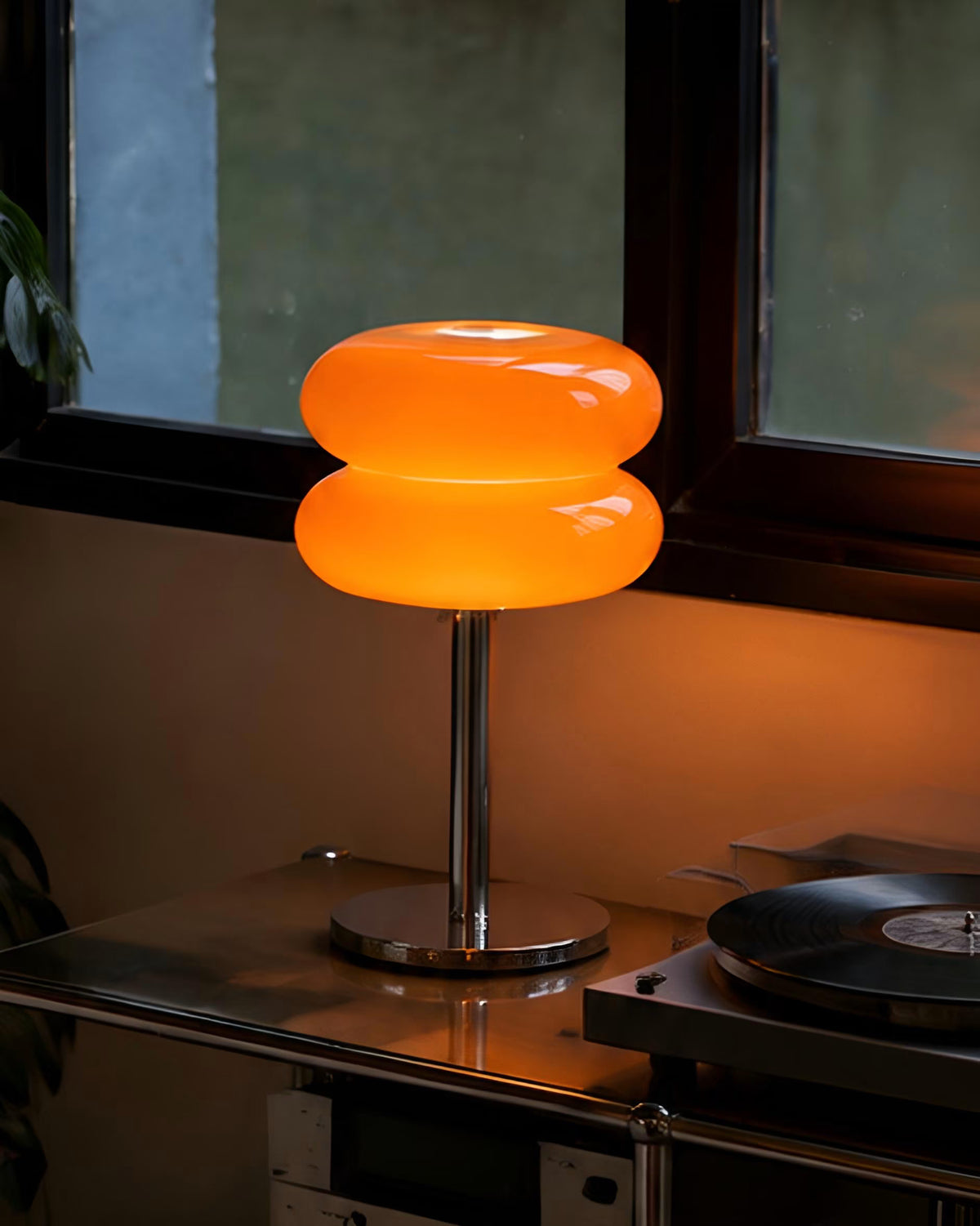 Macaron orange glass table lamp casting a warm glow in a styled living room