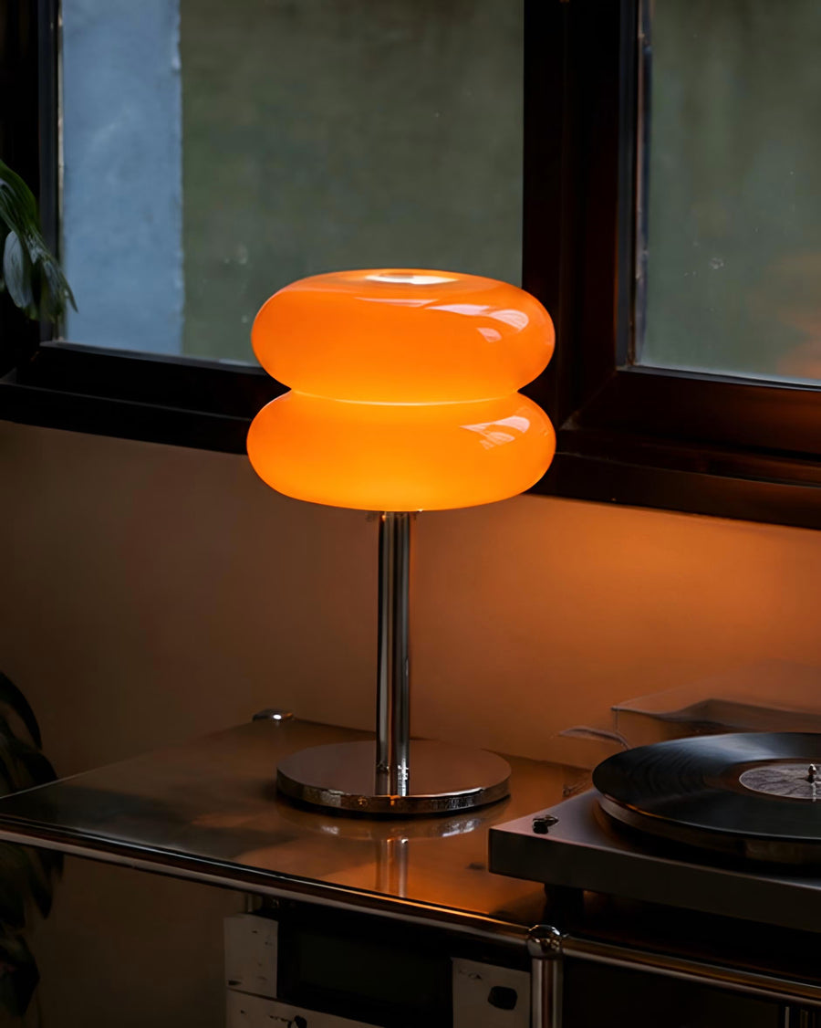 Macaron orange glass table lamp casting a warm glow in a styled living room