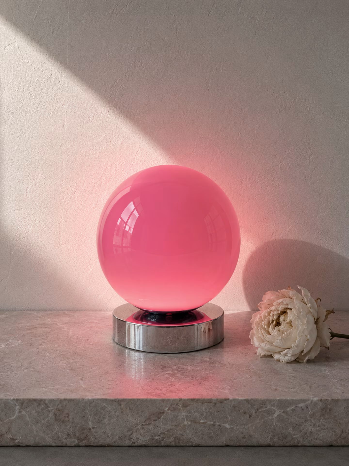 Nova Aurora pink glass globe table lamp on a low chrome-finish base