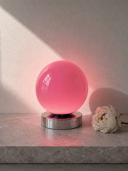 Nova Aurora pink glass globe table lamp on a low chrome-finish base