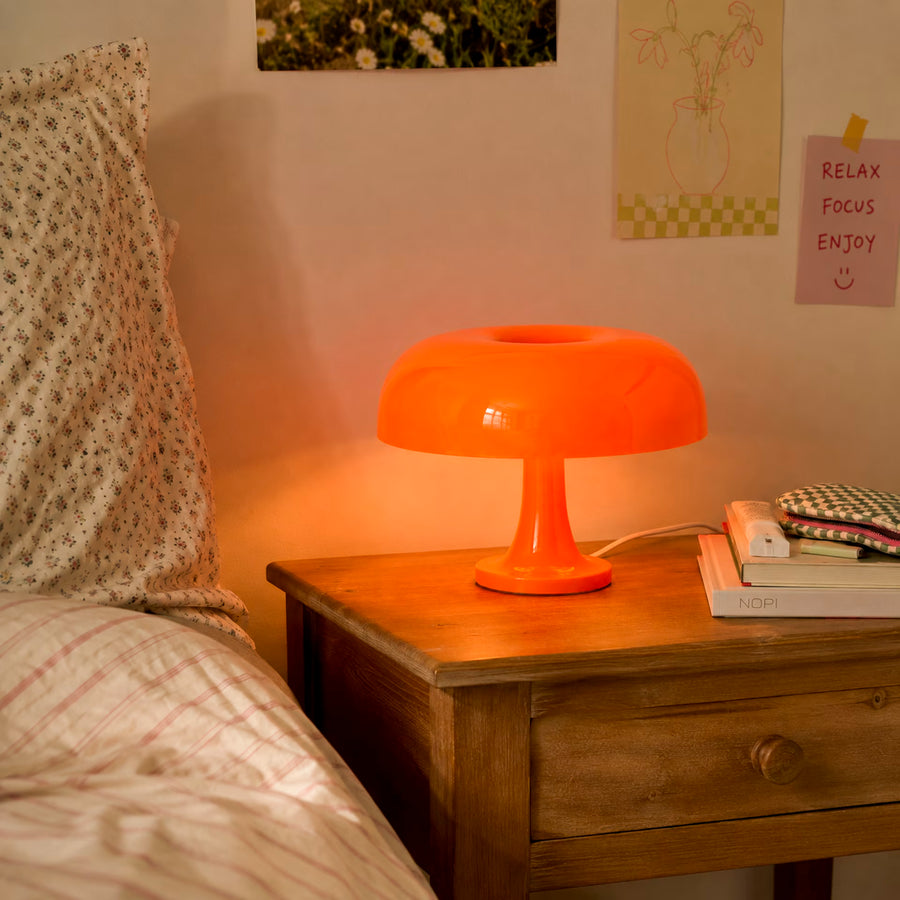 Lit orange mushroom desk lamp on a wooden bedside table