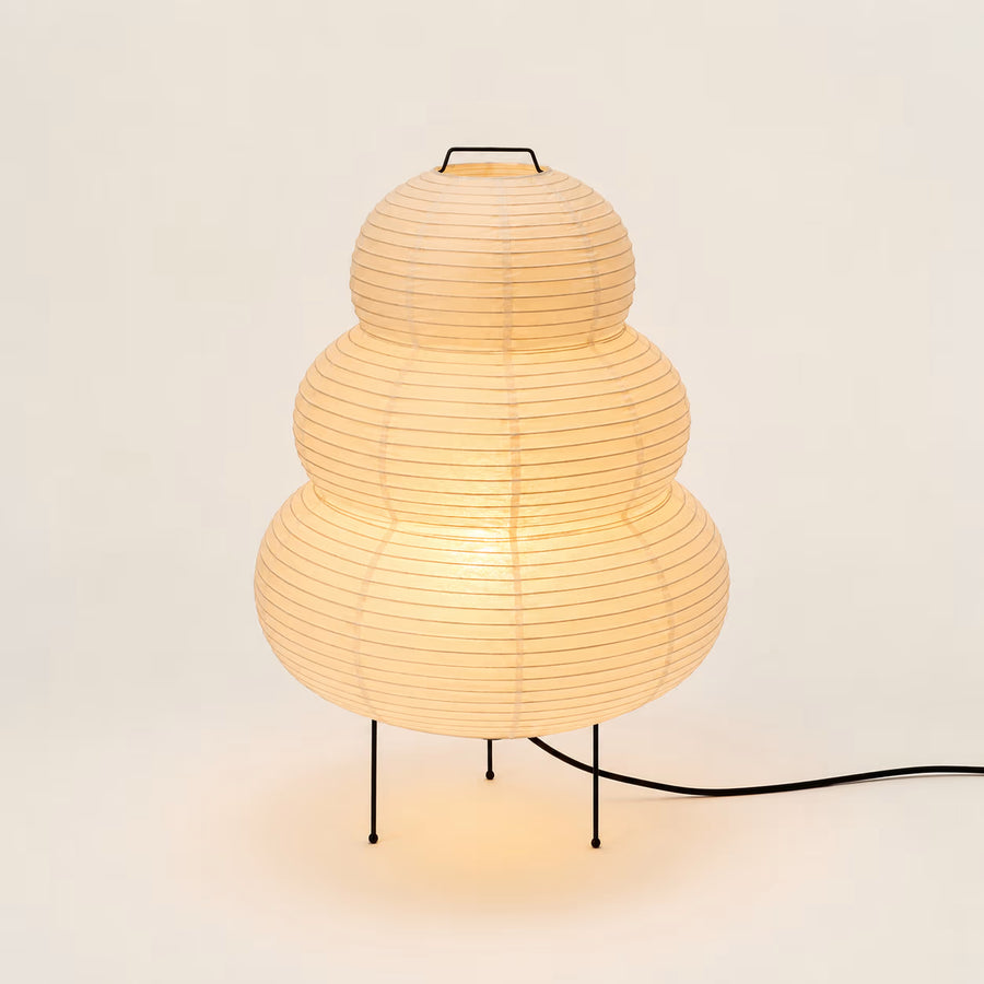 Japanese Hikaru rice-paper lamp glowing warmly on a black iron tripod