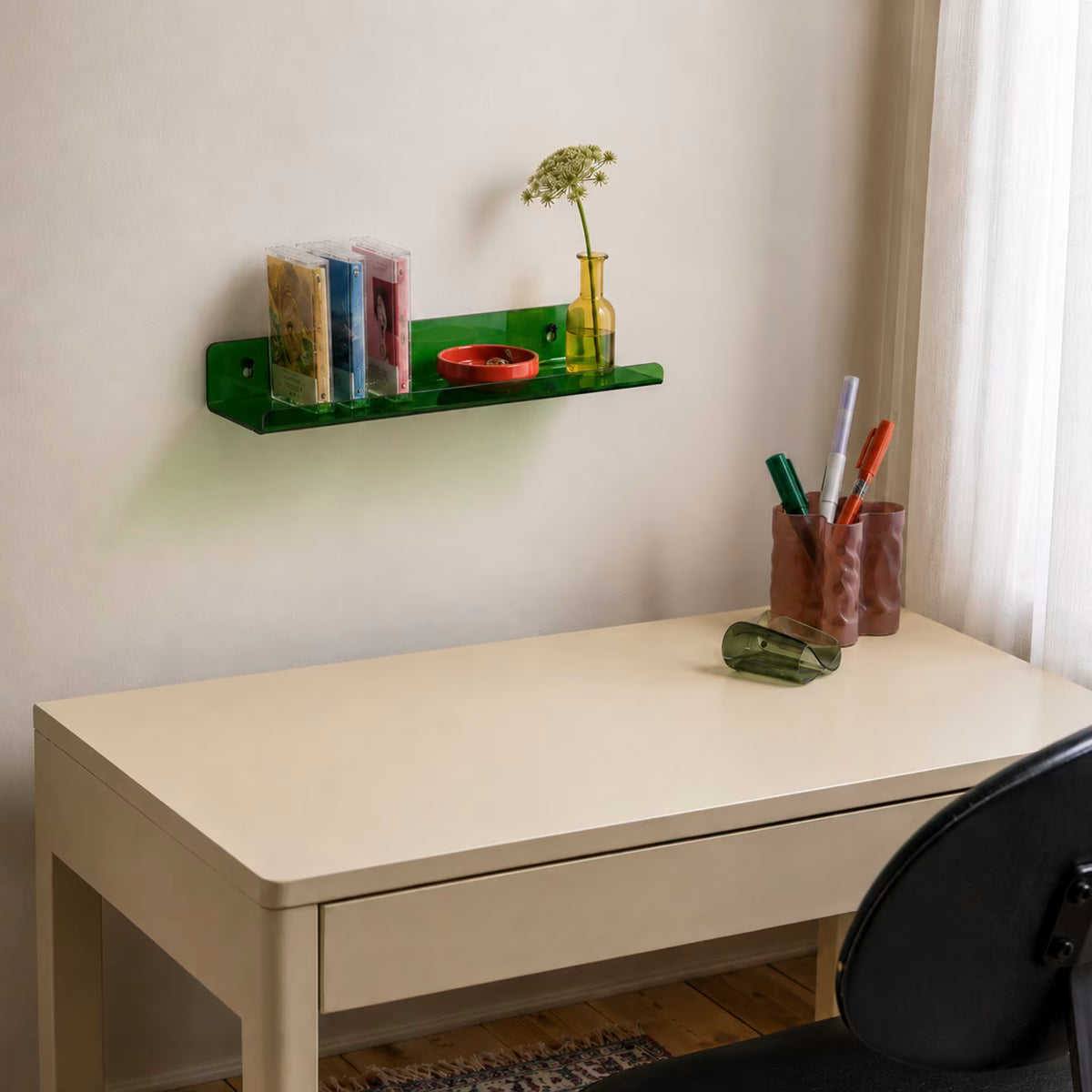 Green acrylic wall shelf holding music cases and accessories above a desk