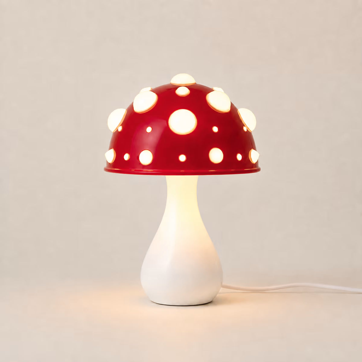 The Manita Lamp with a glossy red spotted dome and sculptural white base