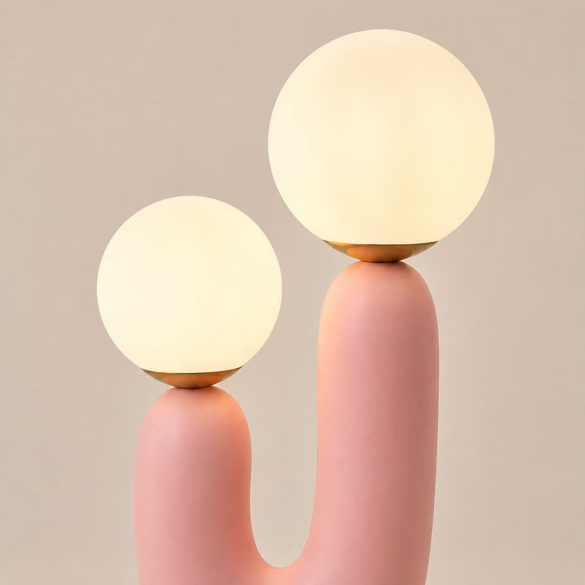 Pink sculptural table lamp illuminated through two rounded glass shades